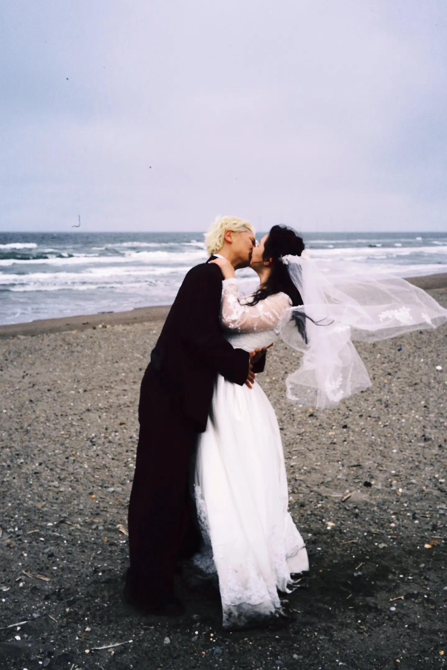 北海道冬季海边风中亲吻的恋人婚纱照