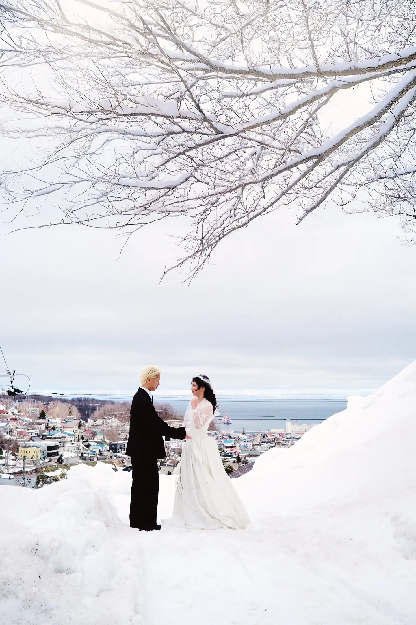 北海道雪坡与海港背景中的婚纱照远景